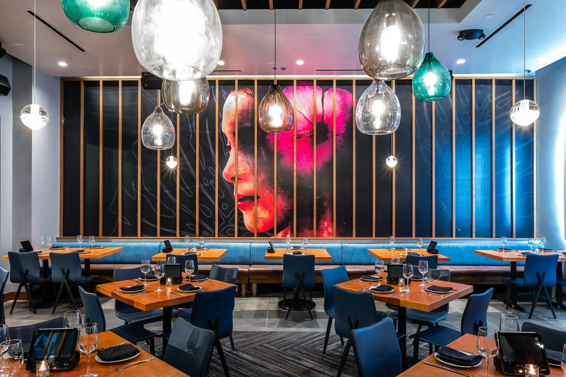 Interior of the Kona Grill Riverton location–a modern design with glass chandeliers, a wall of a mural of a woman's face
