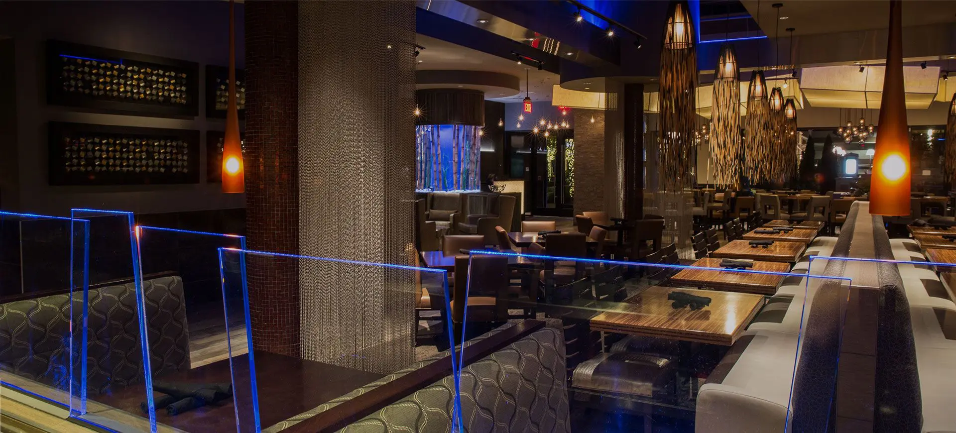 Interior of Kona Grill El Paso, TX view of a dining room with blue and golden lighting, and chandeliers with long tassel