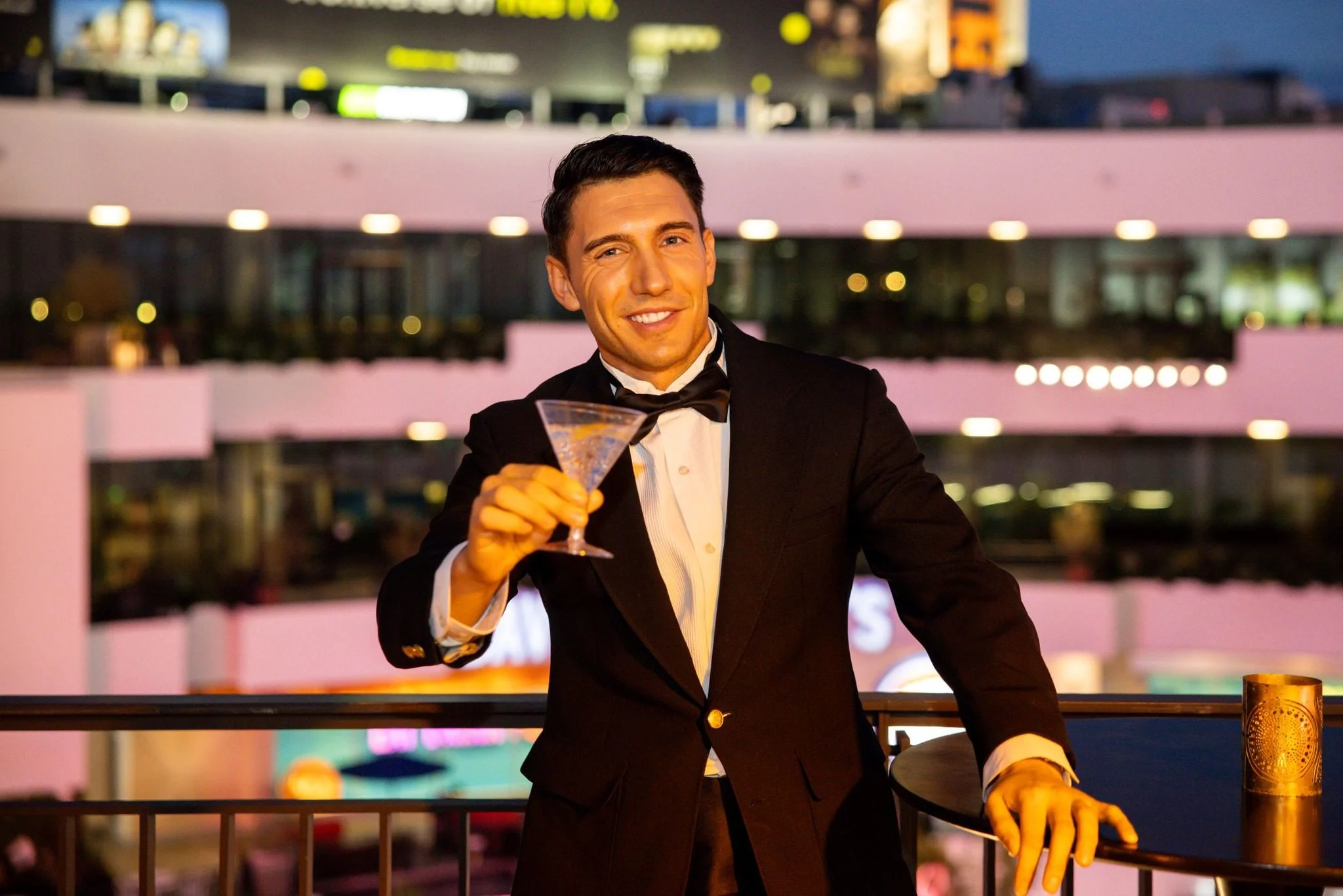 Exclusive VIP scene of a man in a tuxedo toasting with a drink on a balcony.
