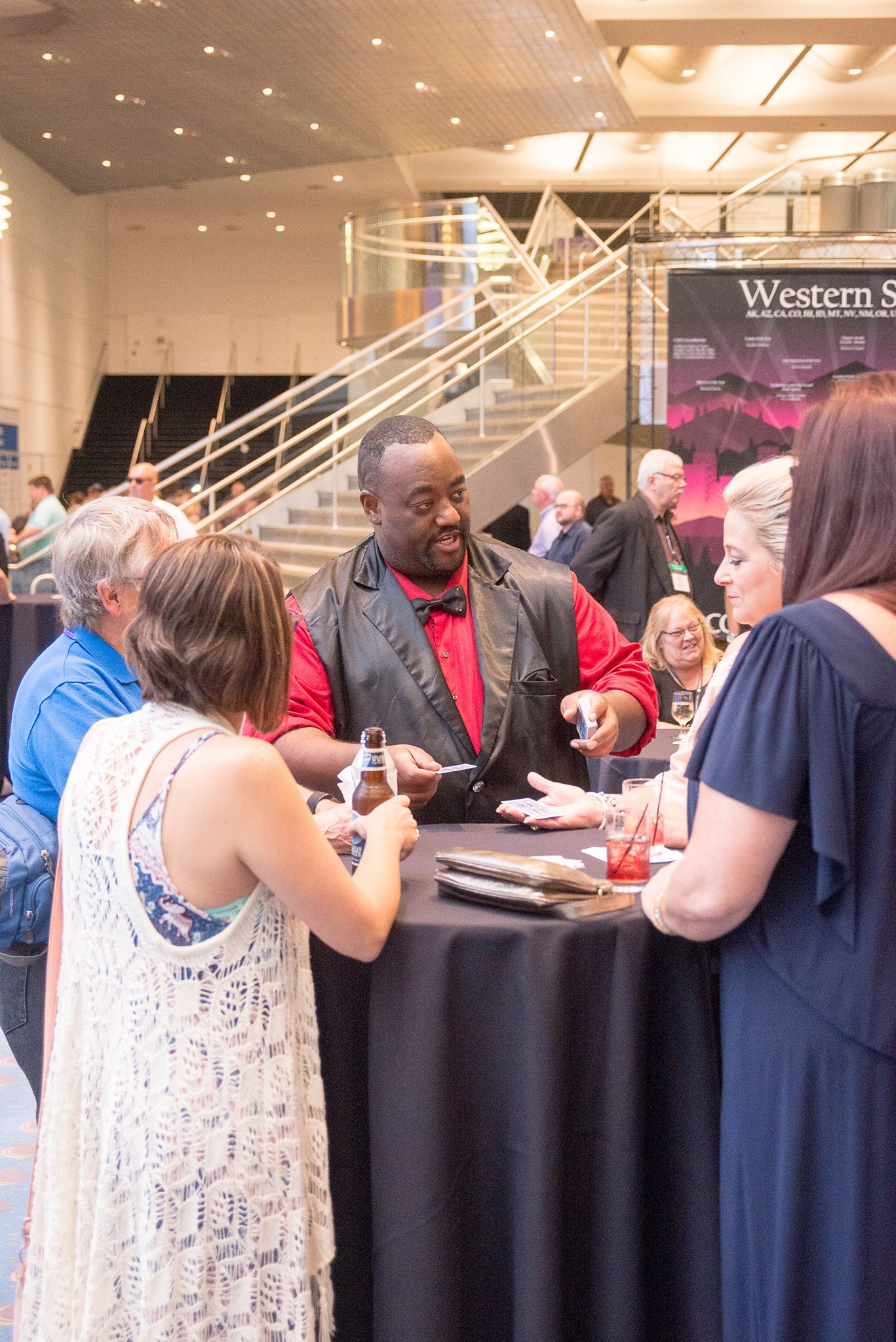 Dewayne Hill performing close-up card magic for guests gathered around a table at an event