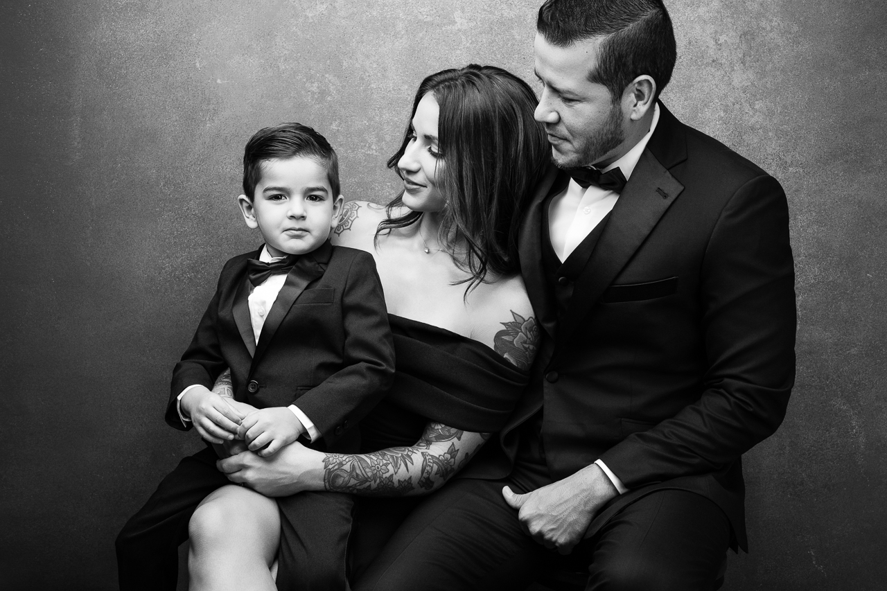 Black-and-white studio portrait of a family of three in formal attire.
