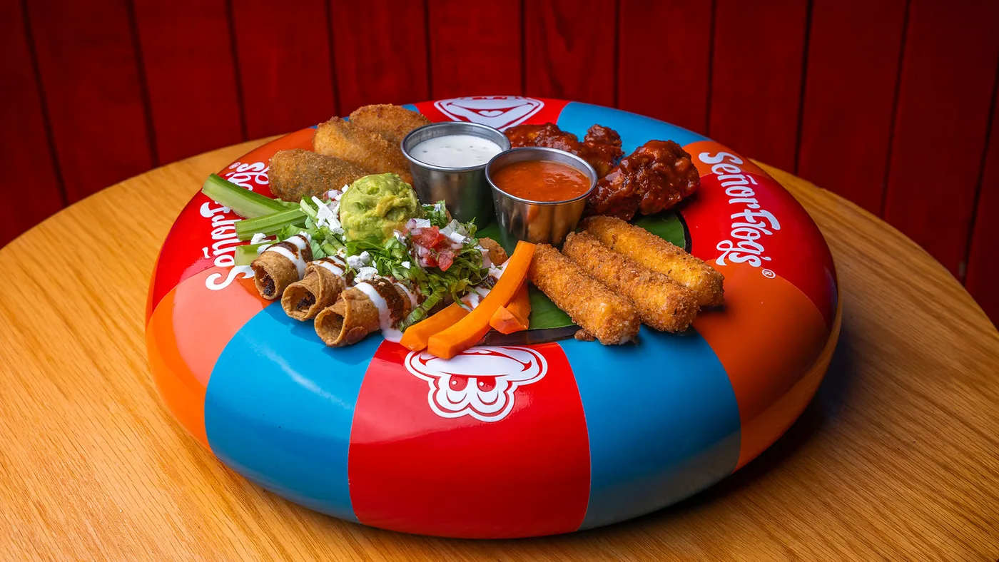 Sampler platter served in a Señor Frog's inflatable float, with taquitos, wings and guacamole