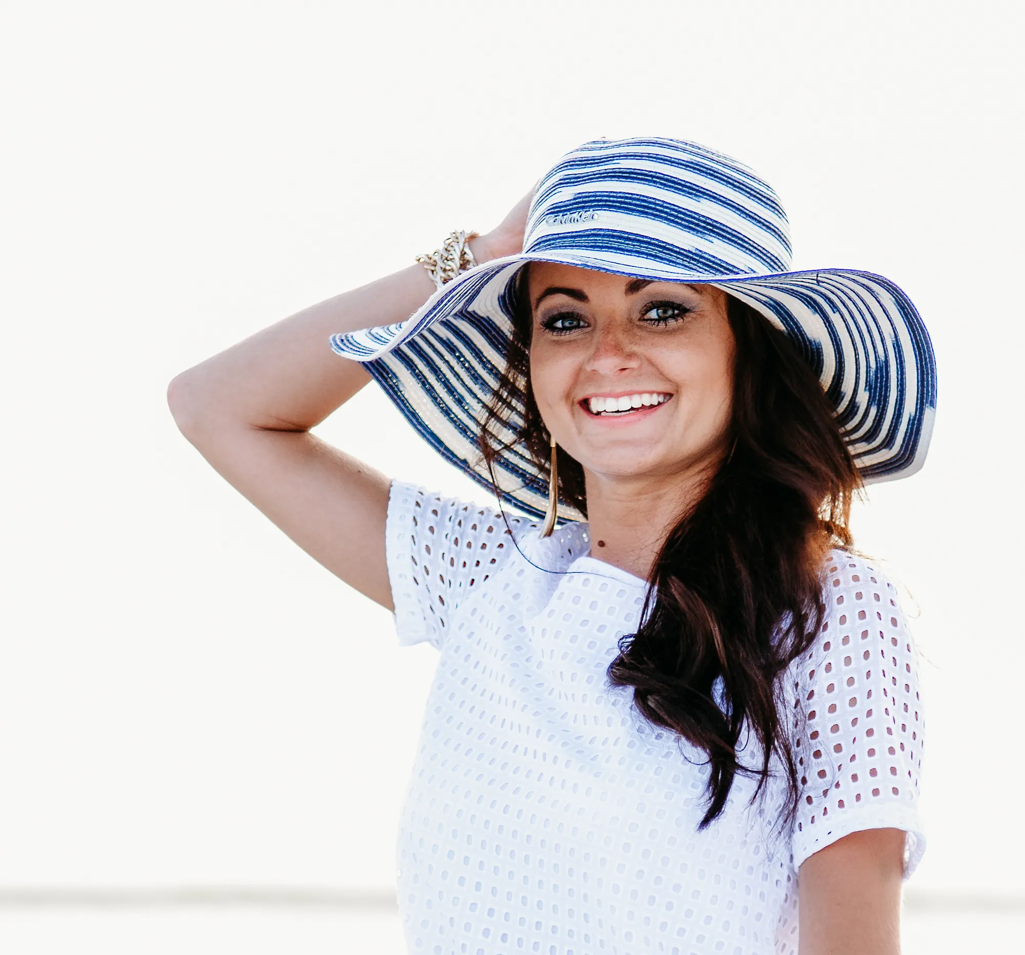A senior girl adorned in a blue and white striped hat captured by a senior photographer at florida beach