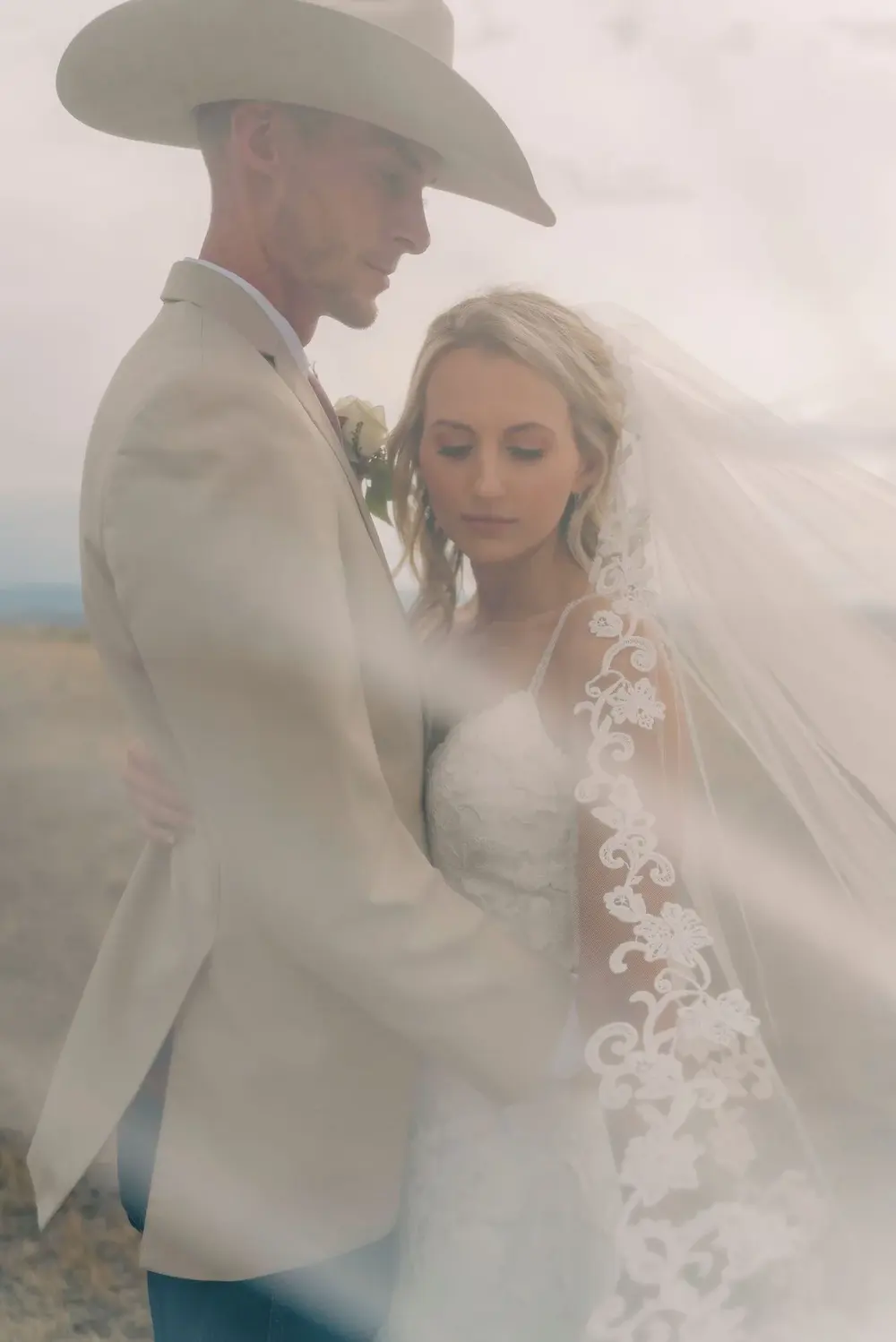 A bride and groom share a tender moment amidst a misty desert backdrop.