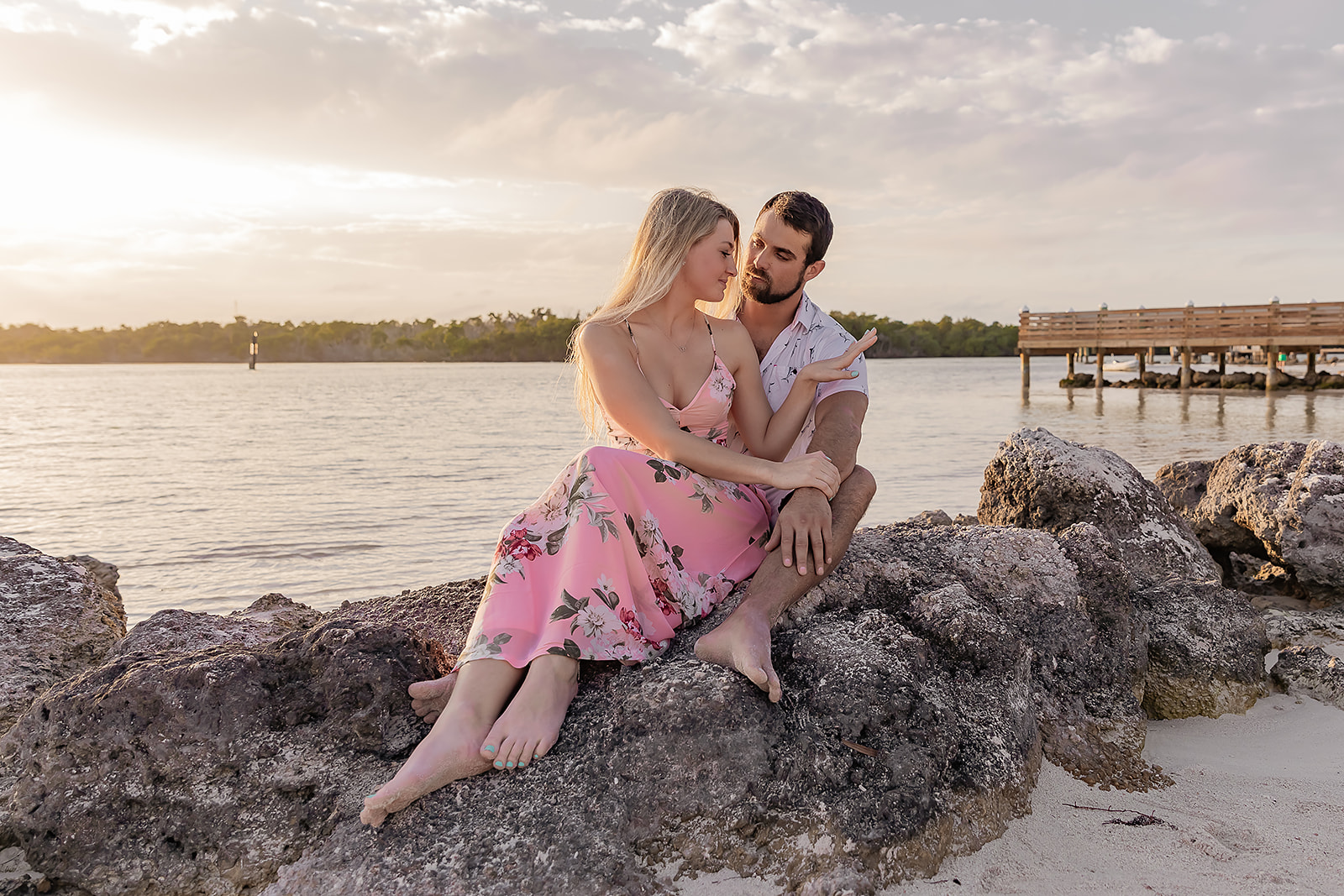 Couple sitting on rock at Sombrero beach showing off her new diamond ring