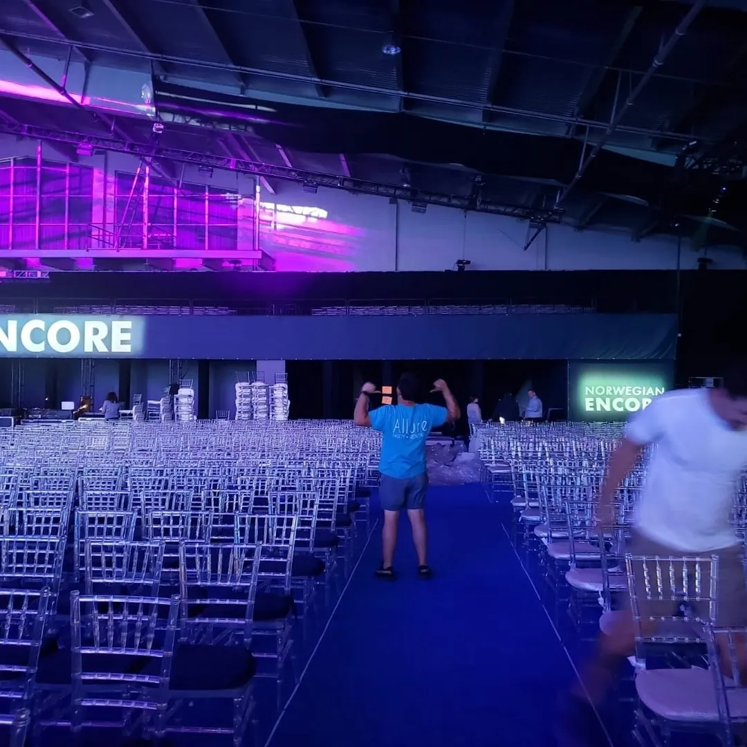 Allure crew member in a branded shirt among thousands of clear Chiavari chairs at the Norwegian Encore event