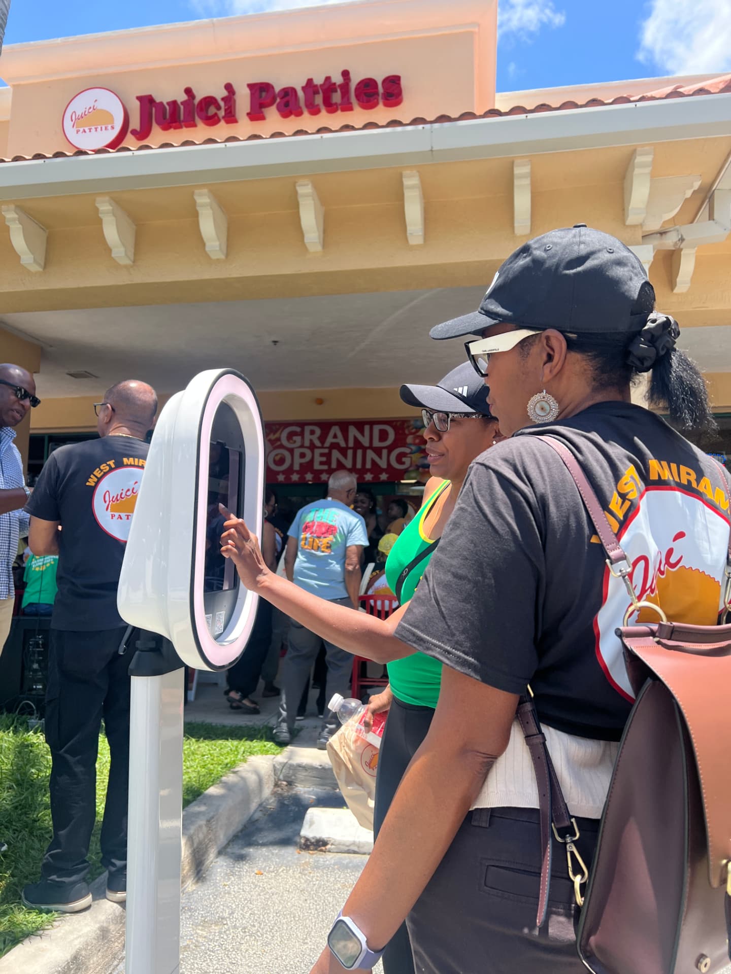 Guests using the SnapJoy SnapBar photo booth in front of the Juici Patties West Miramar storefront