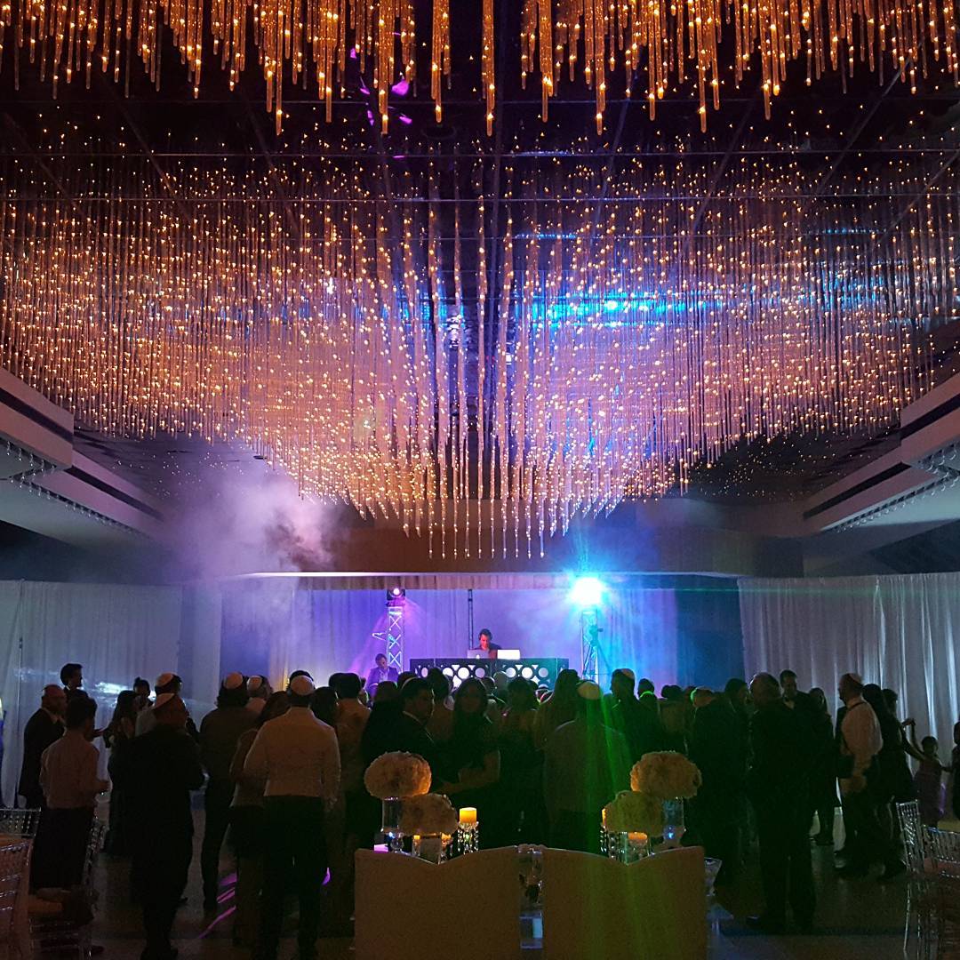 The Aventura ballroom's signature cascading crystal-bead chandelier raft glowing amber over the dance floor, with t
