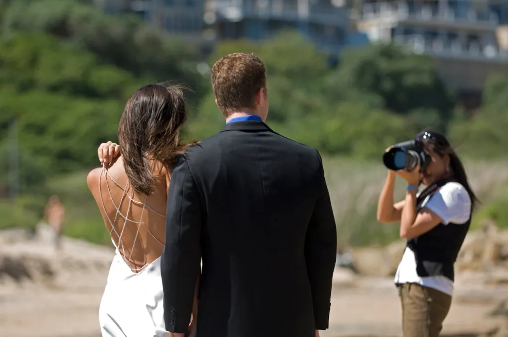 Couple posing outdoors with photographer capturing the moment.