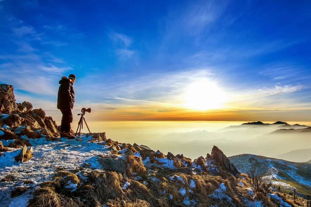 Photographer capturing a stunning mountain sunrise.