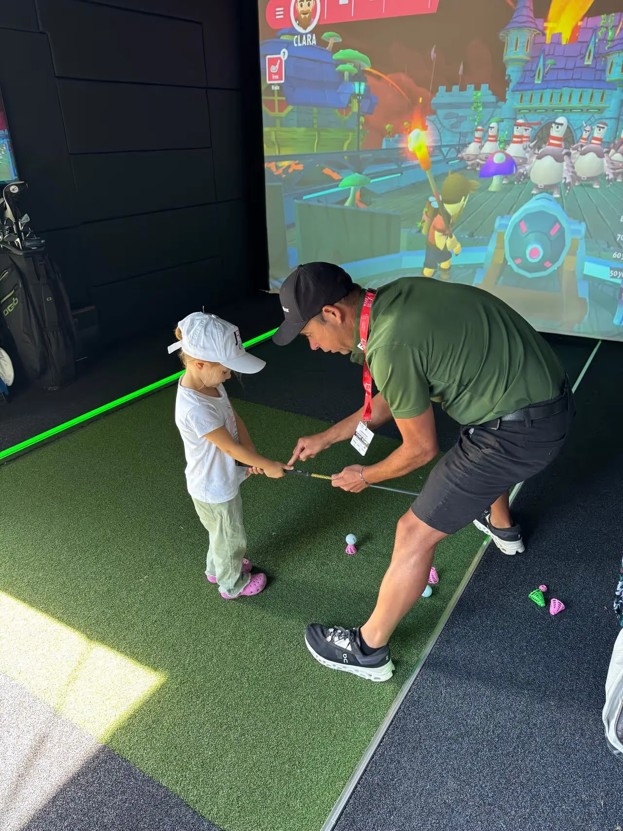 A child learning to golf inside a mobile golf simulator