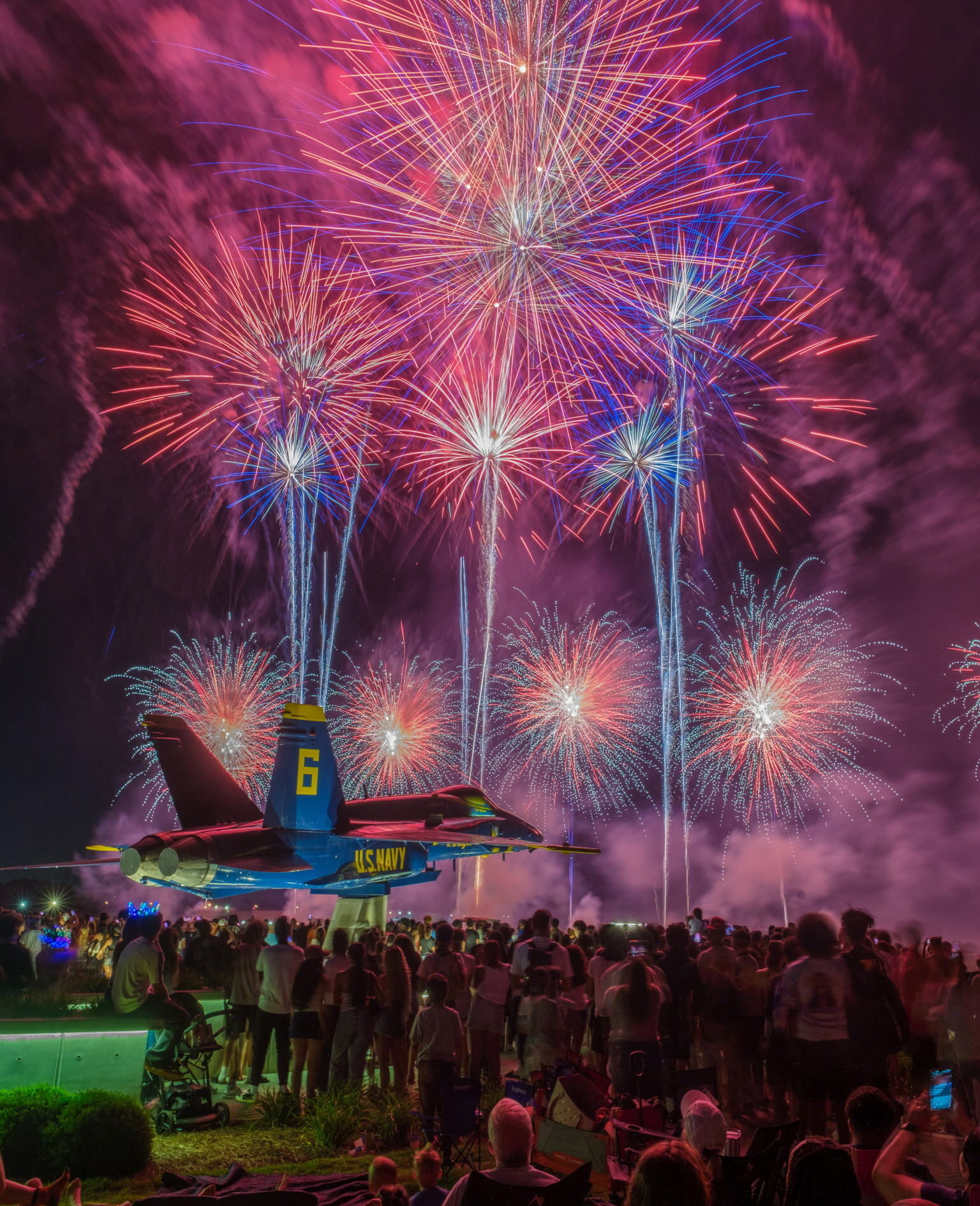Crowd watches red, white, and blue custom fireworks display over a U.S. Navy Blue Angels jet memorial at the America 250