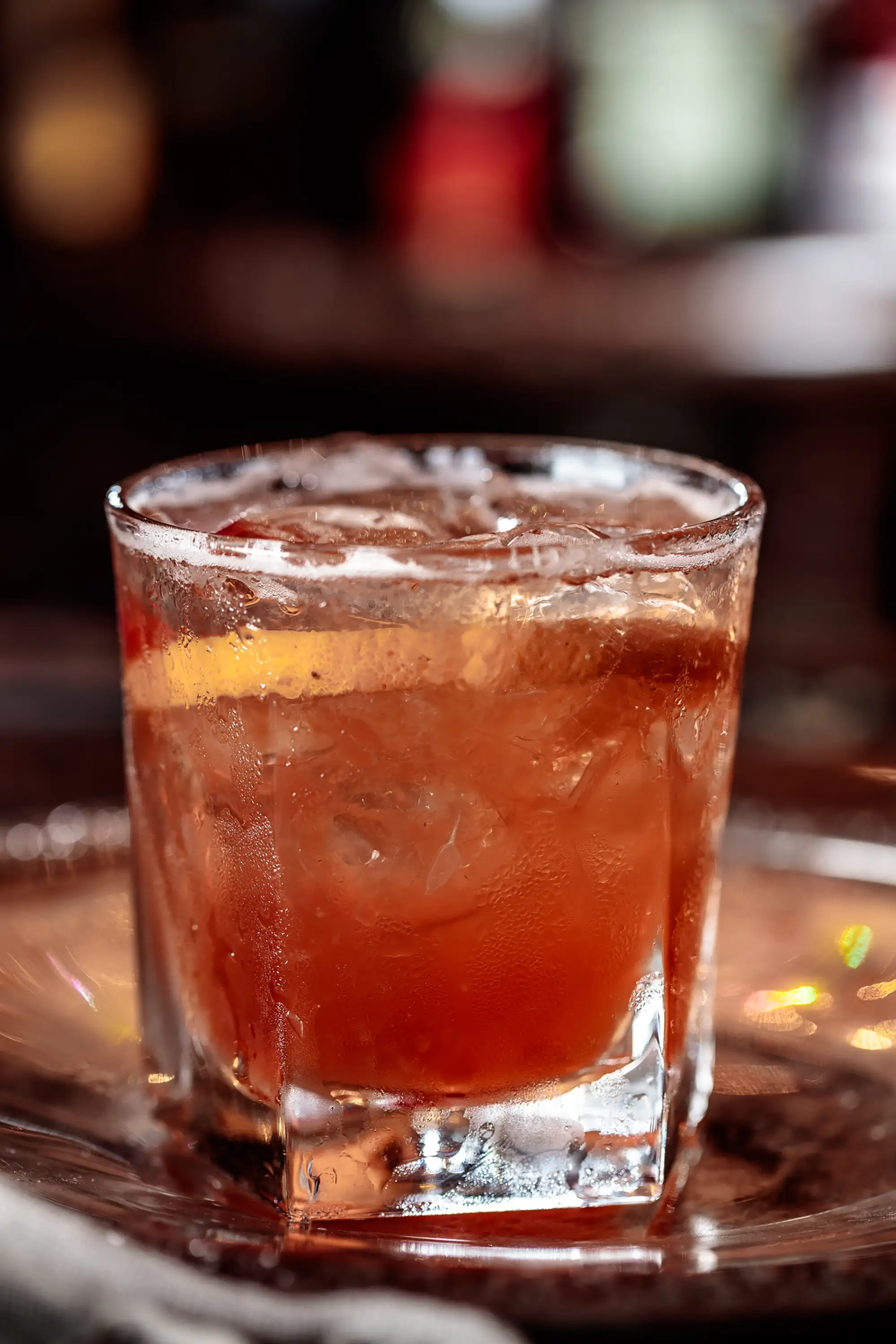 Amber cocktail on the rocks with an orange slice, served on a silver tray
