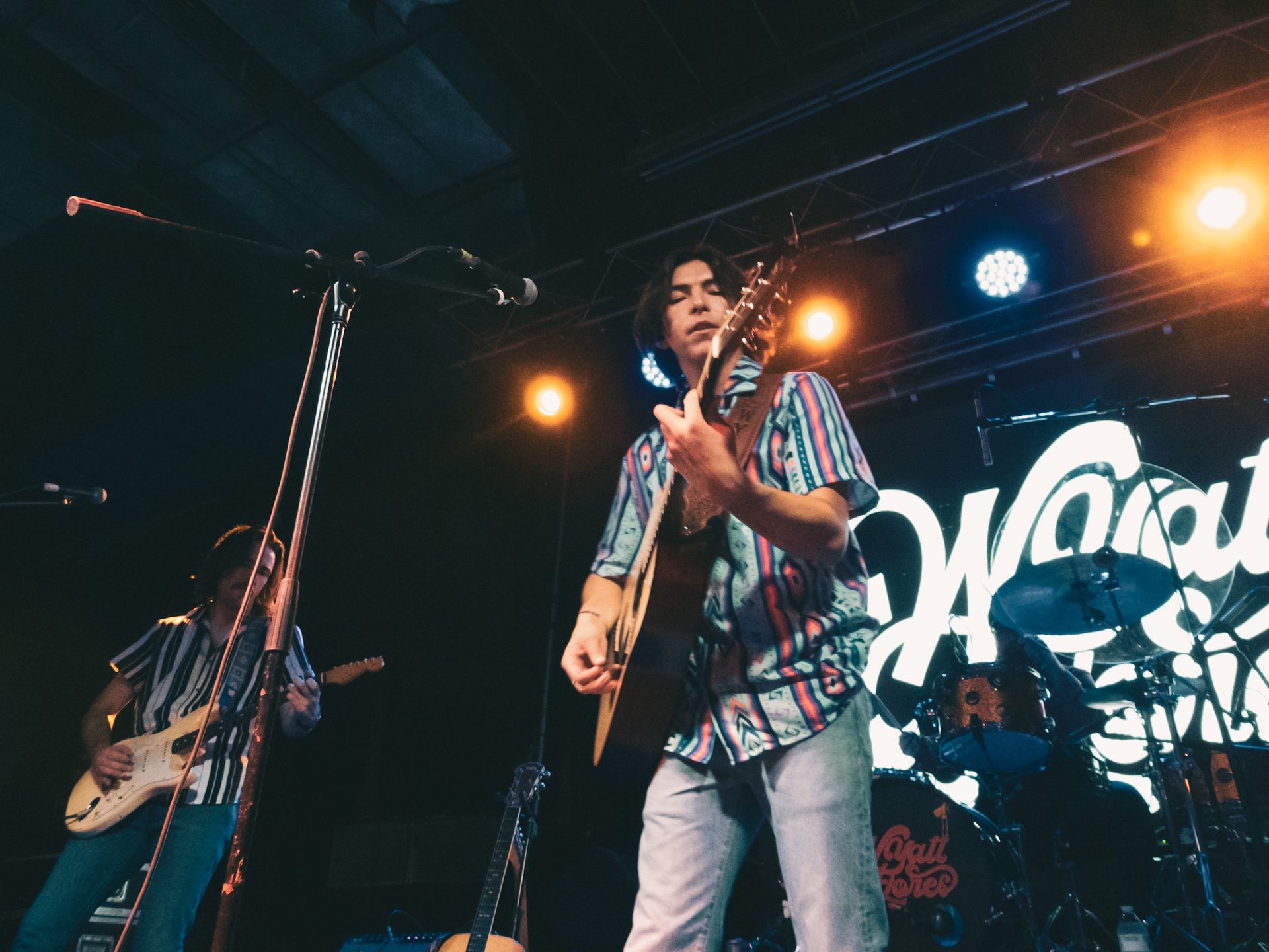 A man is playing a guitar on stage in front of a microphone.