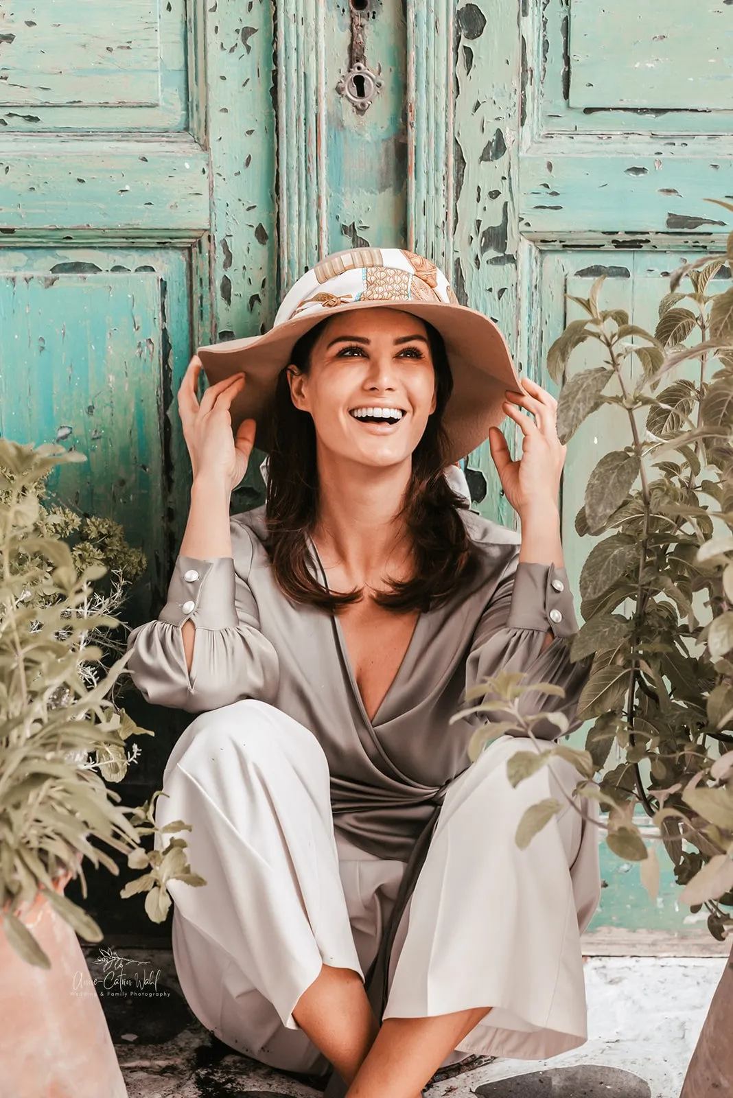 A woman leaning against a wall holding her hat during a portrait photo session
