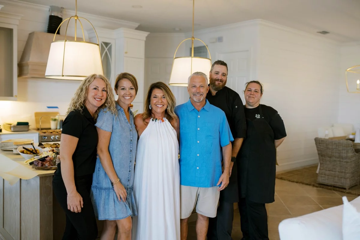 Catering Manager Ashley Dignam and other Magnolias staff members standing with two customers at their home while a cater