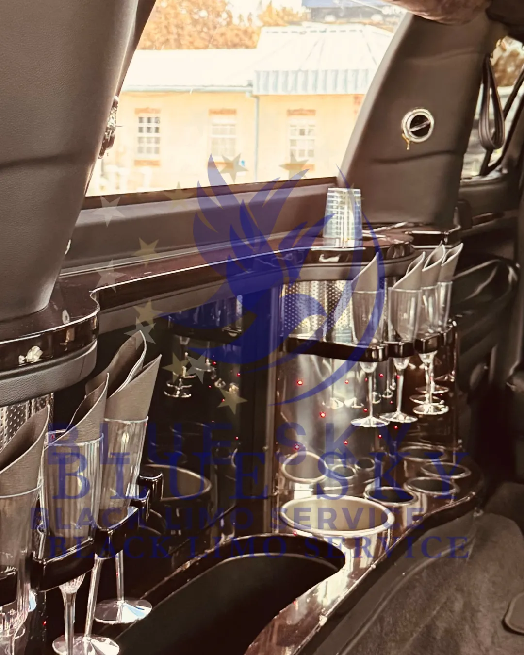 Interior of a luxury limousine featuring an elegant bar setup with various glassware and champagne flutes.