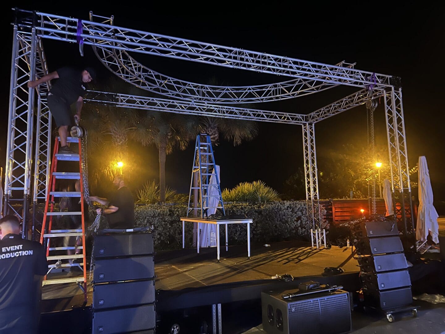 Event crew assembling stage structure at night.