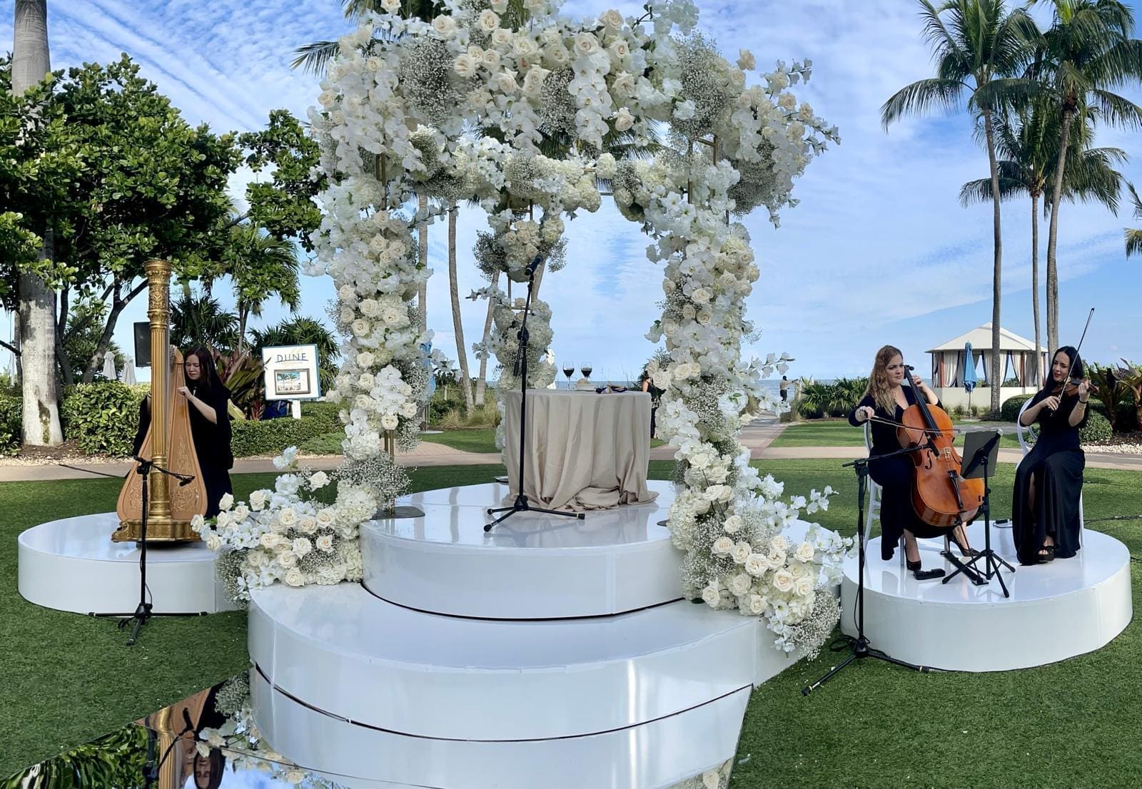 "Musicians performing under a floral arch outdoors."