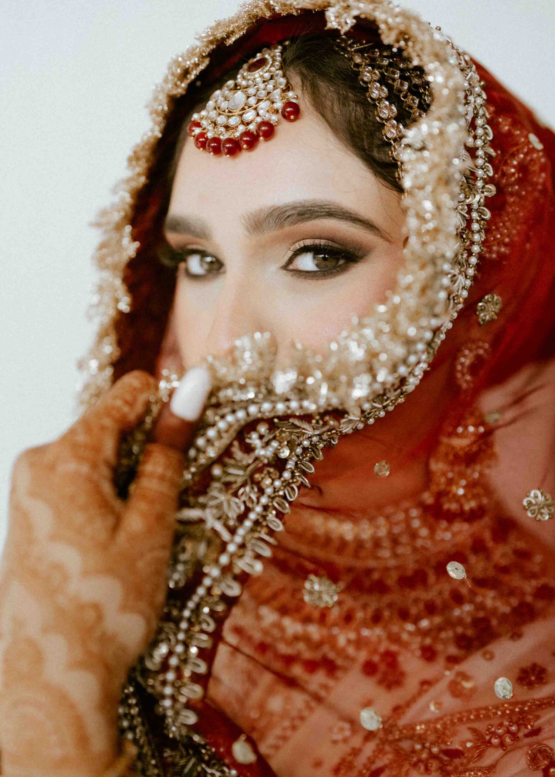 Muslim wedding photography Florida: bridal portrait of a bride with henna holding her embellished red dupatta
